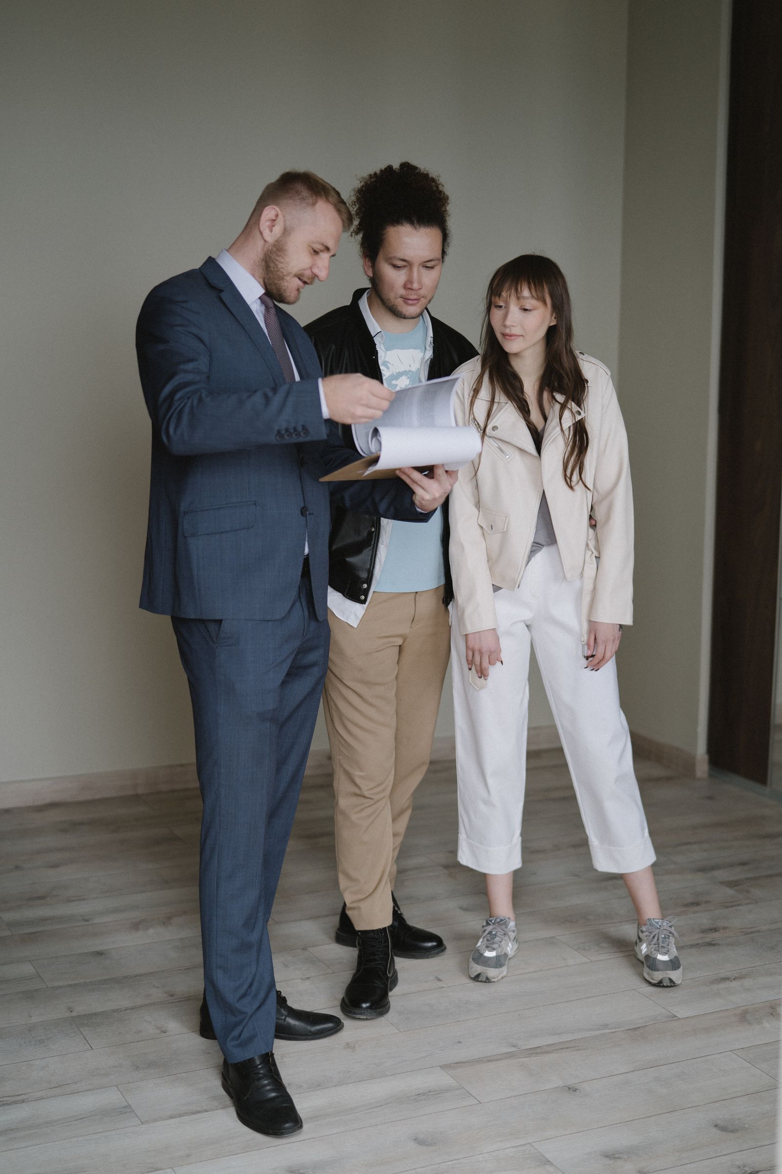 Kaufinteressierte besprechen Unterlagen in einer Wohnung